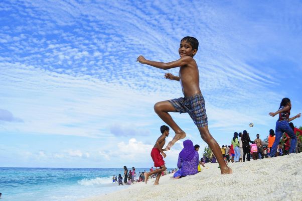 Children enjoying a sunny day on Fuvahmulah Beach, Maldives, filled with laughter and fun.