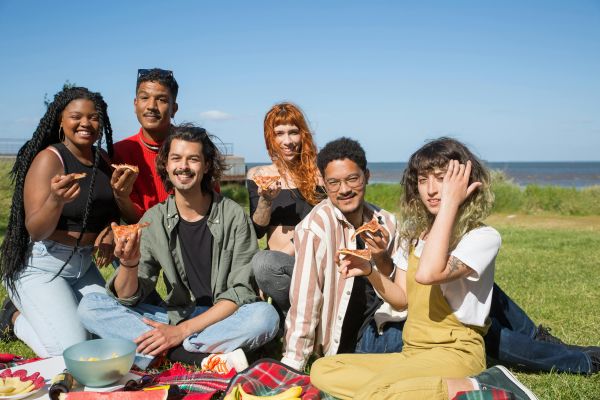 A diverse group of young friends enjoying a sunny picnic outdoors in Portugal.