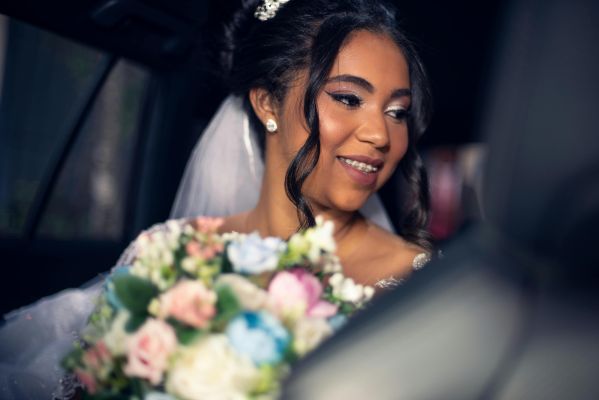 A joyful bride holding a bouquet, sitting in a car, ready for the wedding ceremony.