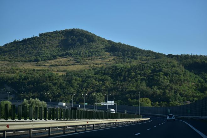 A scenic highway view in Romania, showcasing lush green hills on a sunny day.