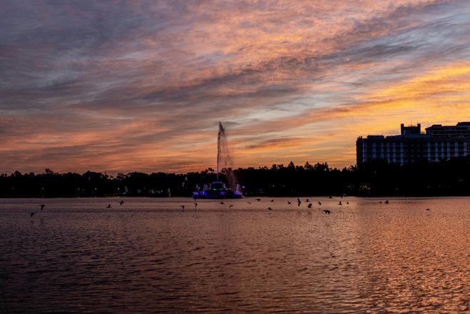 Stunning sunset view of Lake Eola fountain and city skyline with vibrant colors.